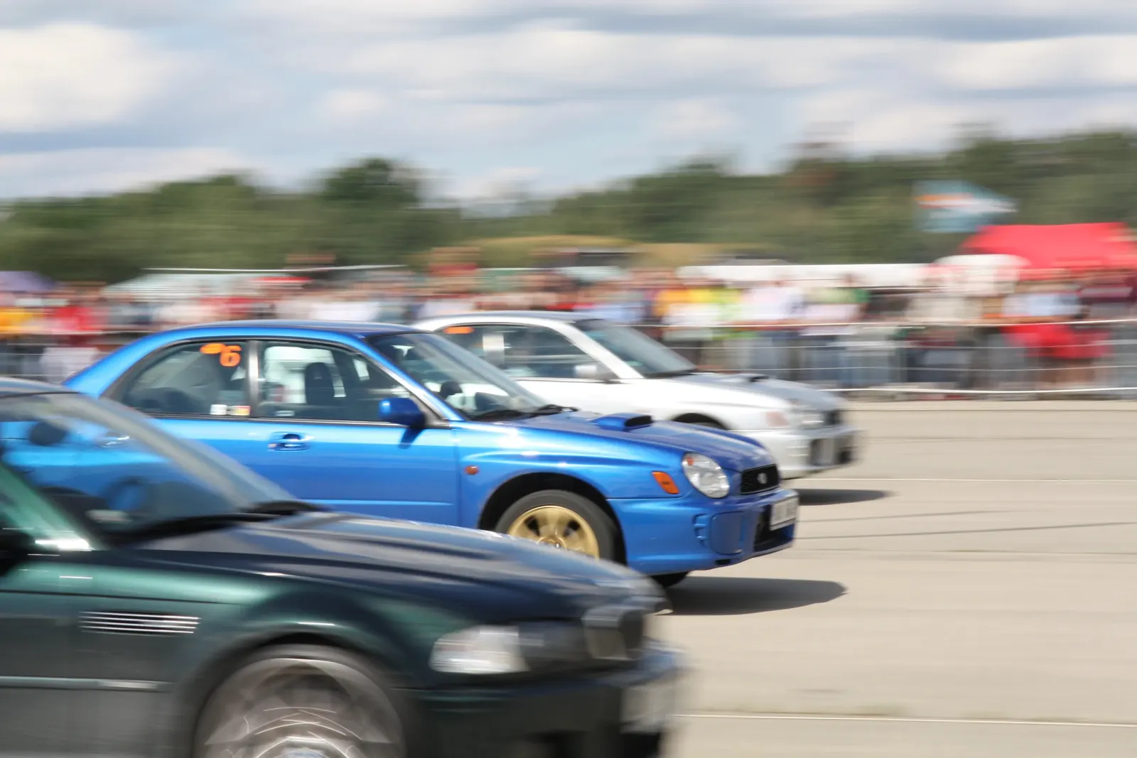 Modrá Subaru Impreza a další auta v pohybové rozostření během sprintu na letišti Hradčany