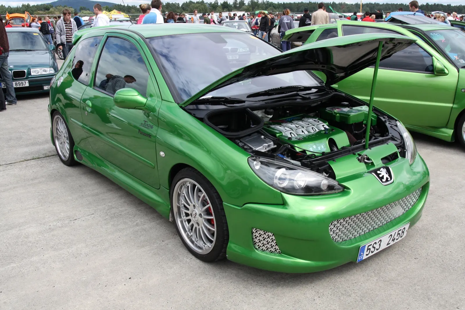Zelený Peugeot 206 s otevřenou kapotou v klubové řadě