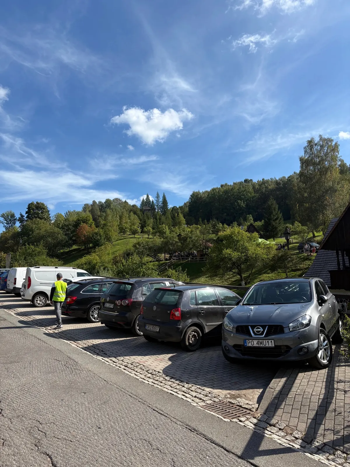 Kaskádovité parkoviště u skanzenu ve Pstrążné, v pozadí zelené kopce