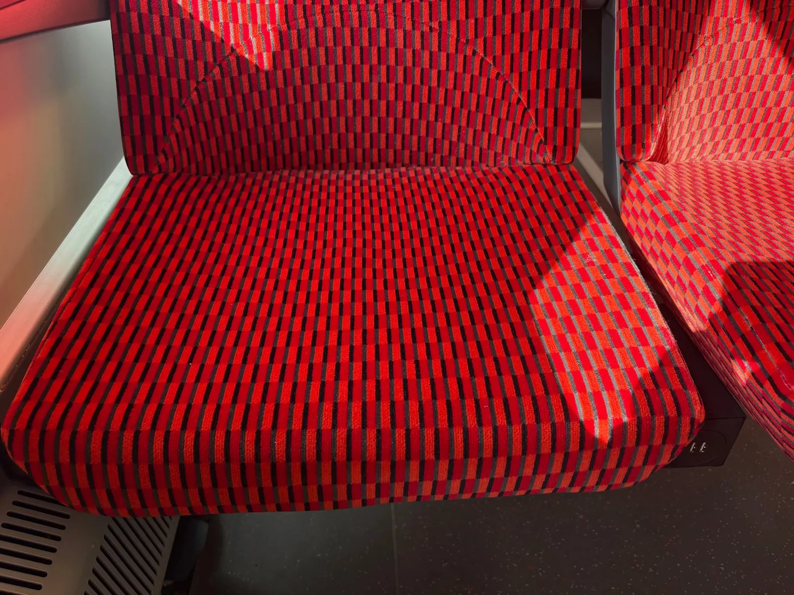 Detail čalounění sedačky druhé třídy - červený a černý káro vzor.