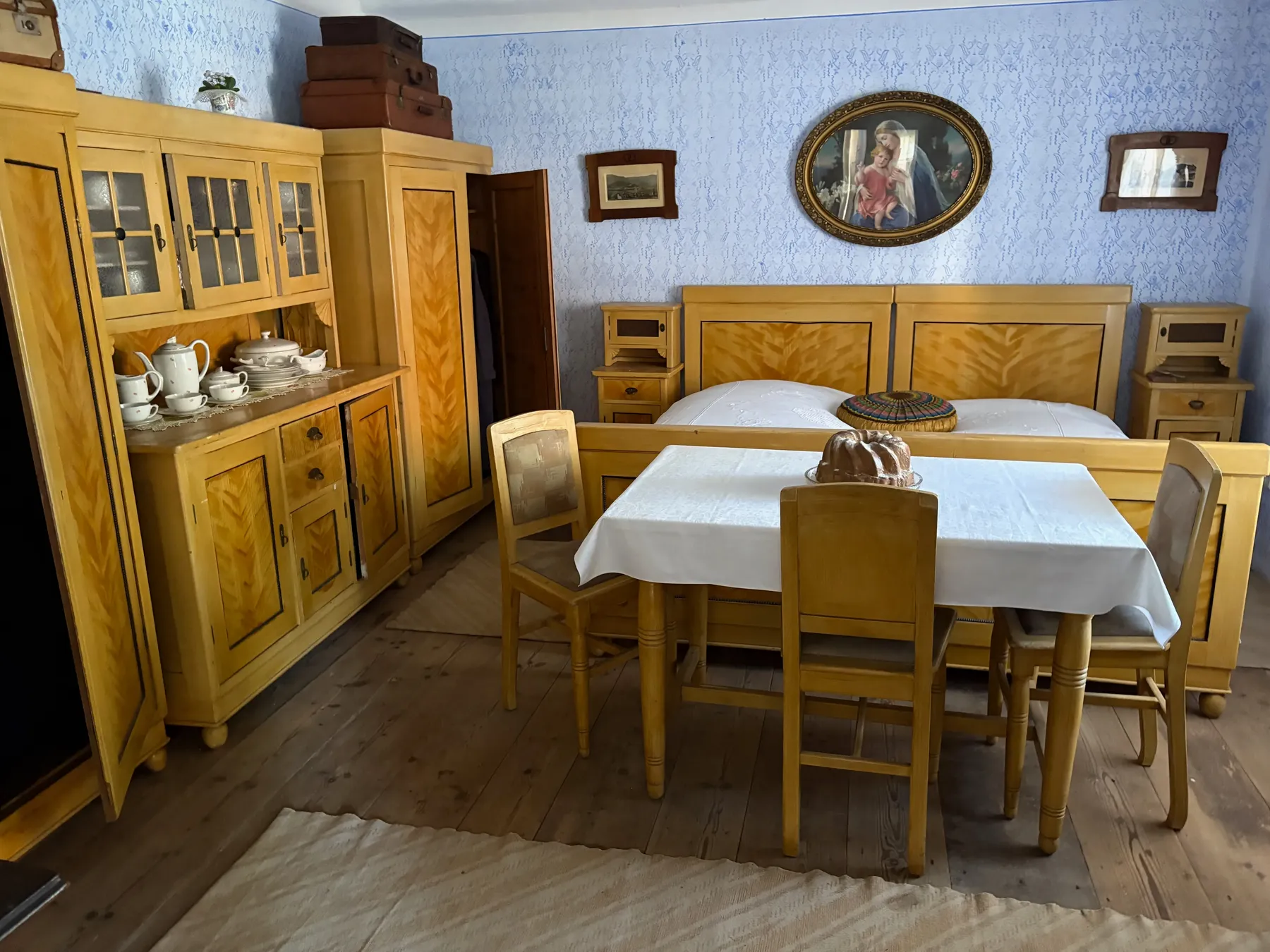 Světlý jídelní kout s vysokým dřevěným kredencem a prostřeným stolem s bílým ubrusem