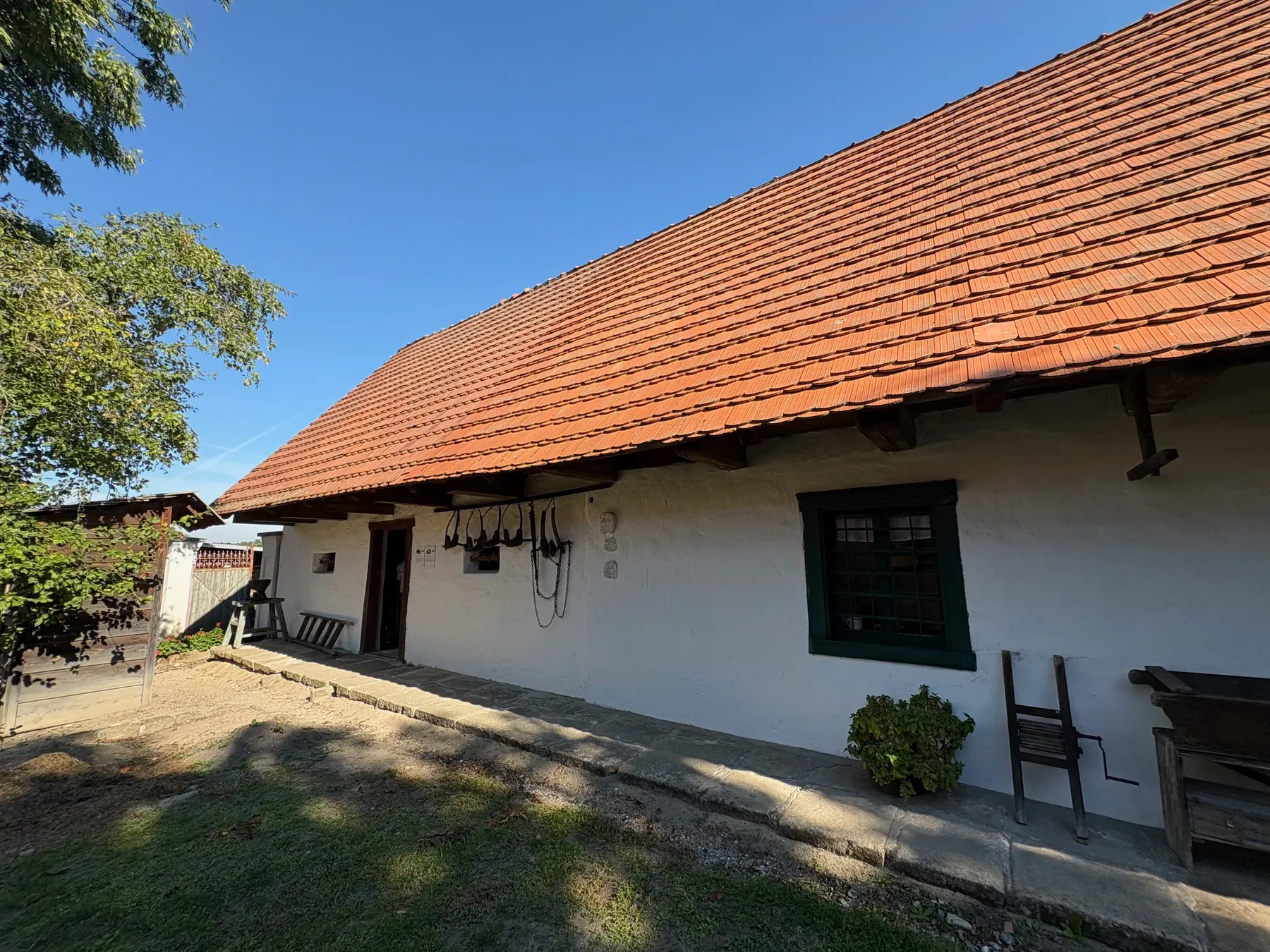 Bílá chalupa se strmou červenou taškovou střechou, dvě okna a přední zápraží
