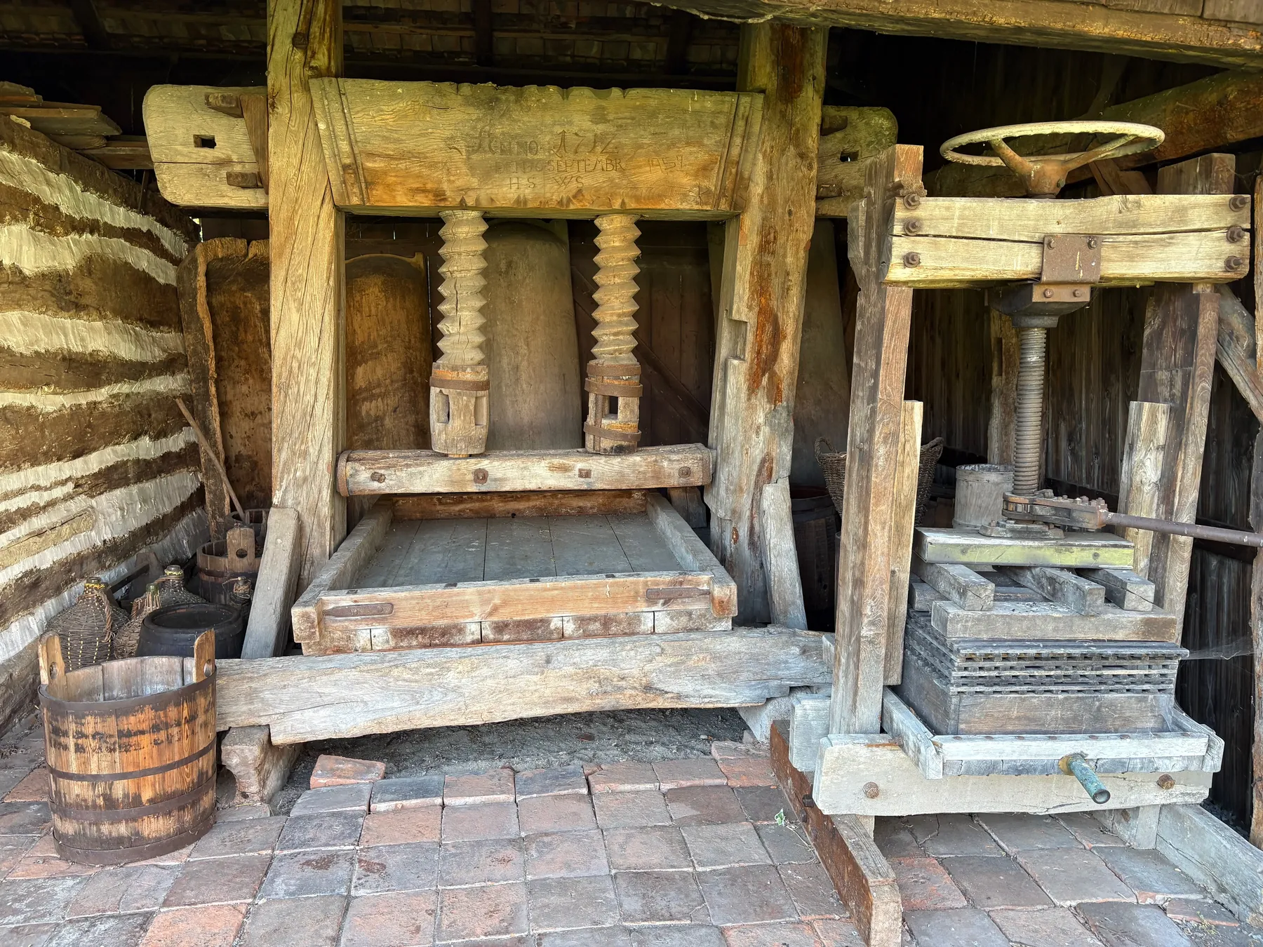Velký dřevěný šroubový lis se dvěma vřeteny, otesaným lisovacím trámem, cihelná podlaha