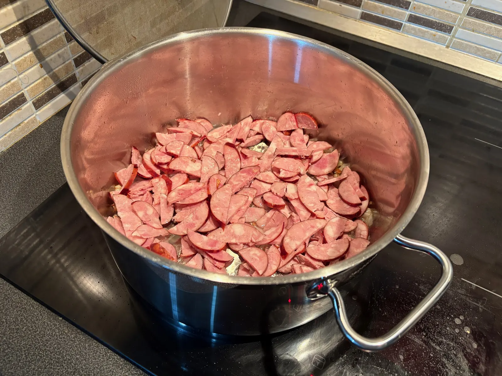 Nakrájená klobása na osmažené cibuli v hrnci