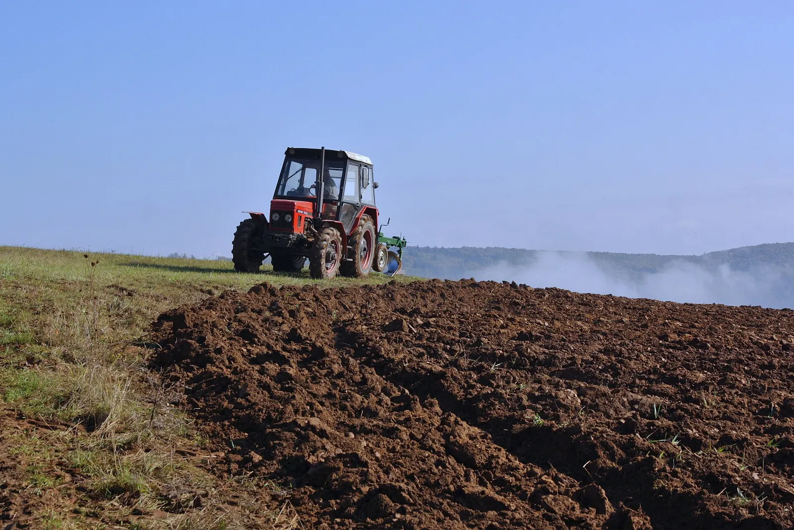 Zetor 7245 s pluhem na poli na kopci u obce Kaly, v údolí mlha